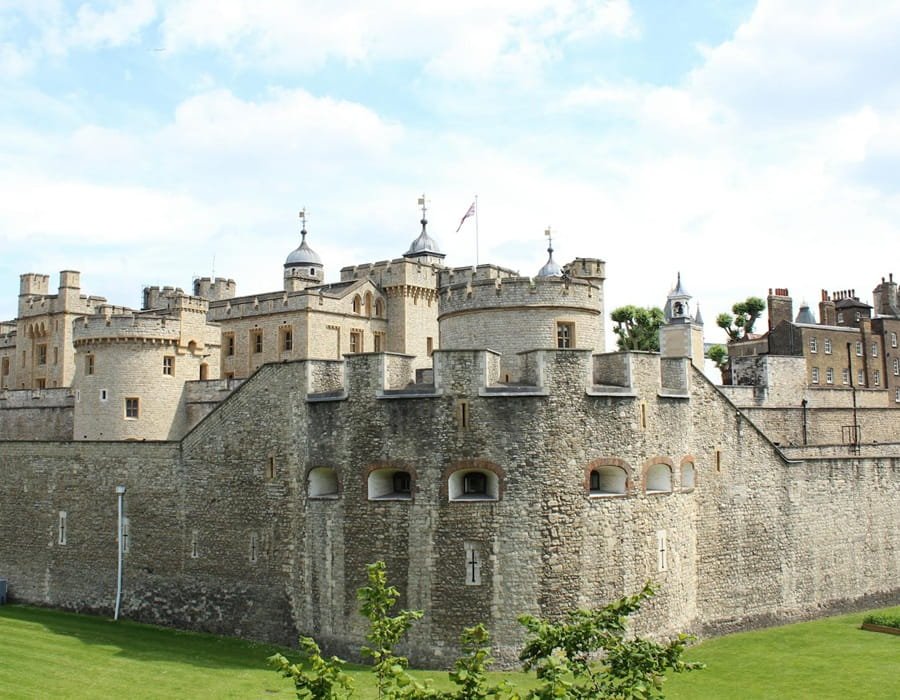 Tower of London fortress wide view with white towers, stone walls, and British flag